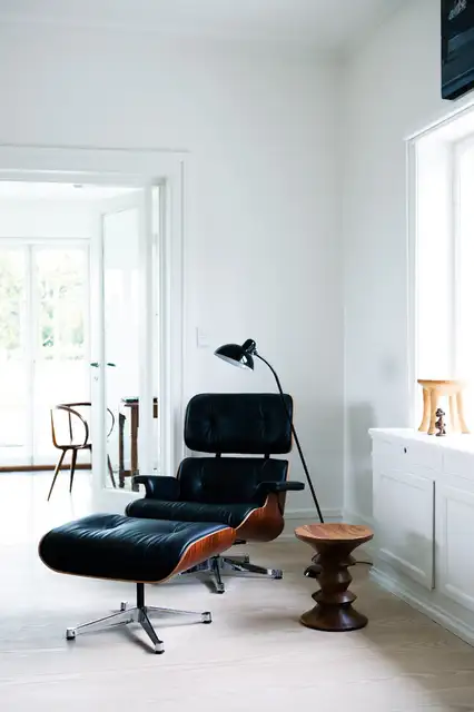 Традиционное кресло Eames Lounge Chair с оттоманкой в углу